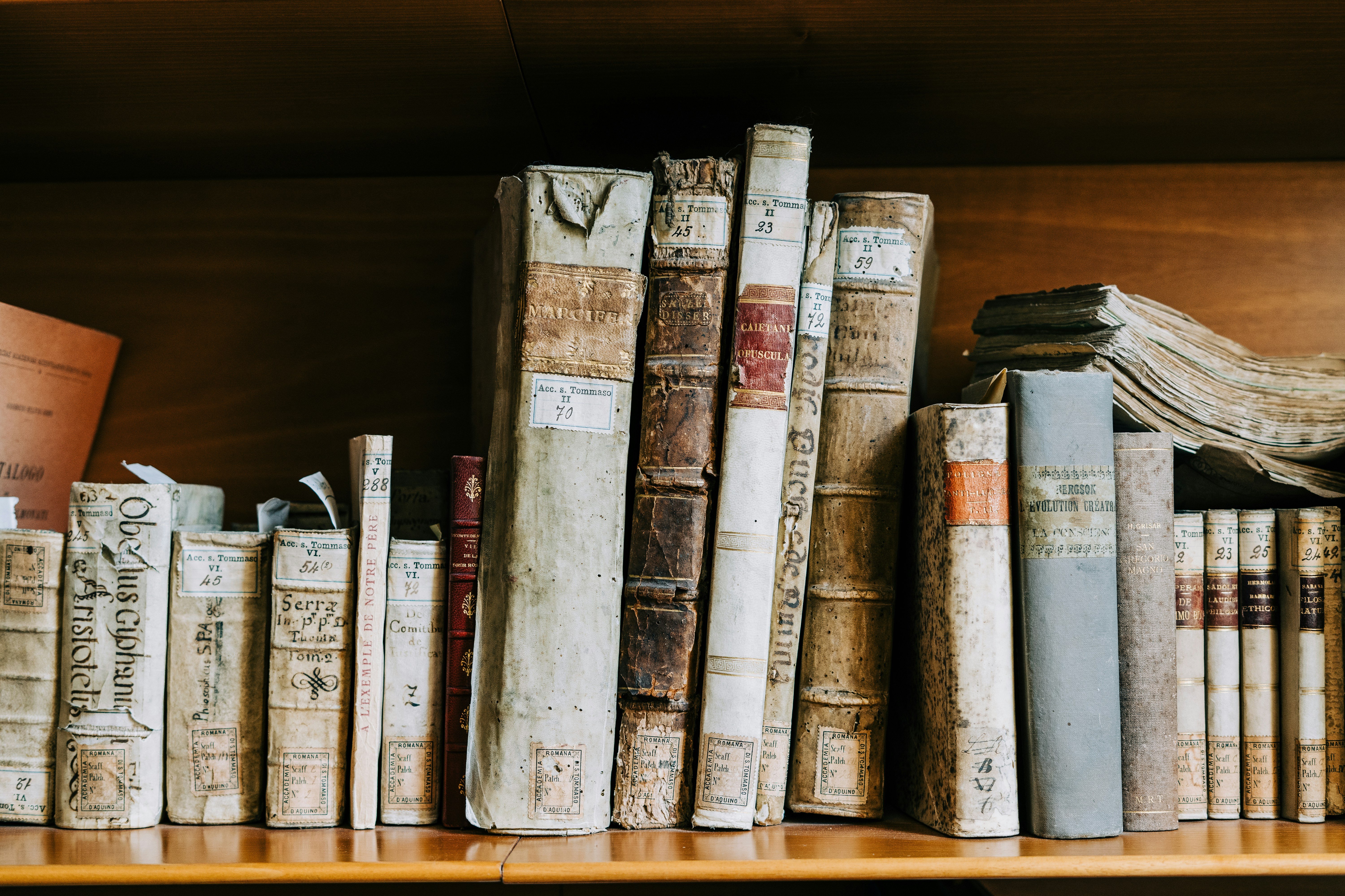 worn leather books on wooden shelf
